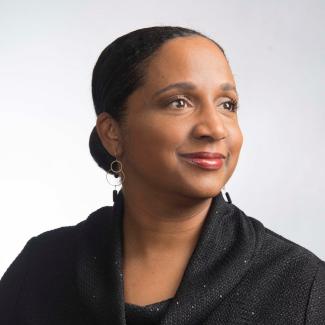 Dr. Daina Ramey Berry poses for a portrait, wearing a black cowlneck sweater against a white background