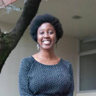 Jennifer Pierre smiles wearing earrings and a polka dotted shirt