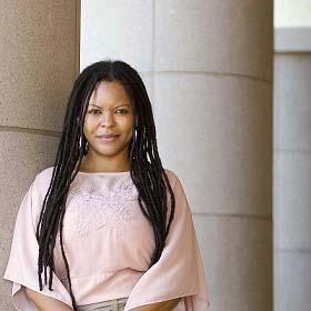 Simone Brown leans against a column wearing a pink shirt